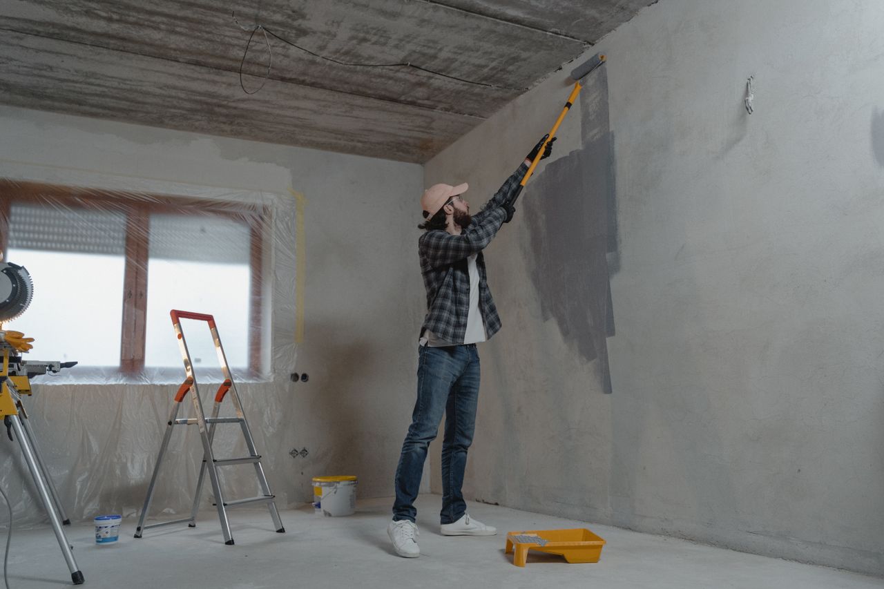 Mastering the First Impression: Your intriguing post title goes here A man painting an interior wall with a roller during a home renovation project.